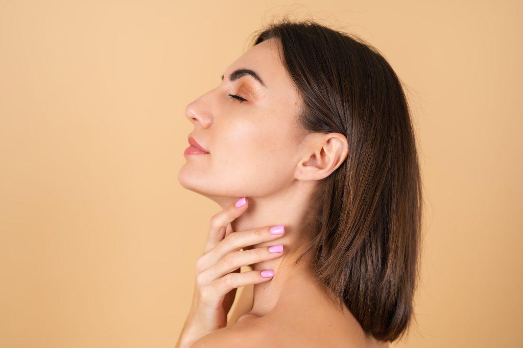 Portrait of a young girl on a beige background with natural makeup, with a light sensual smile, bare shoulders, beauty face, advertising of cosmetics and care